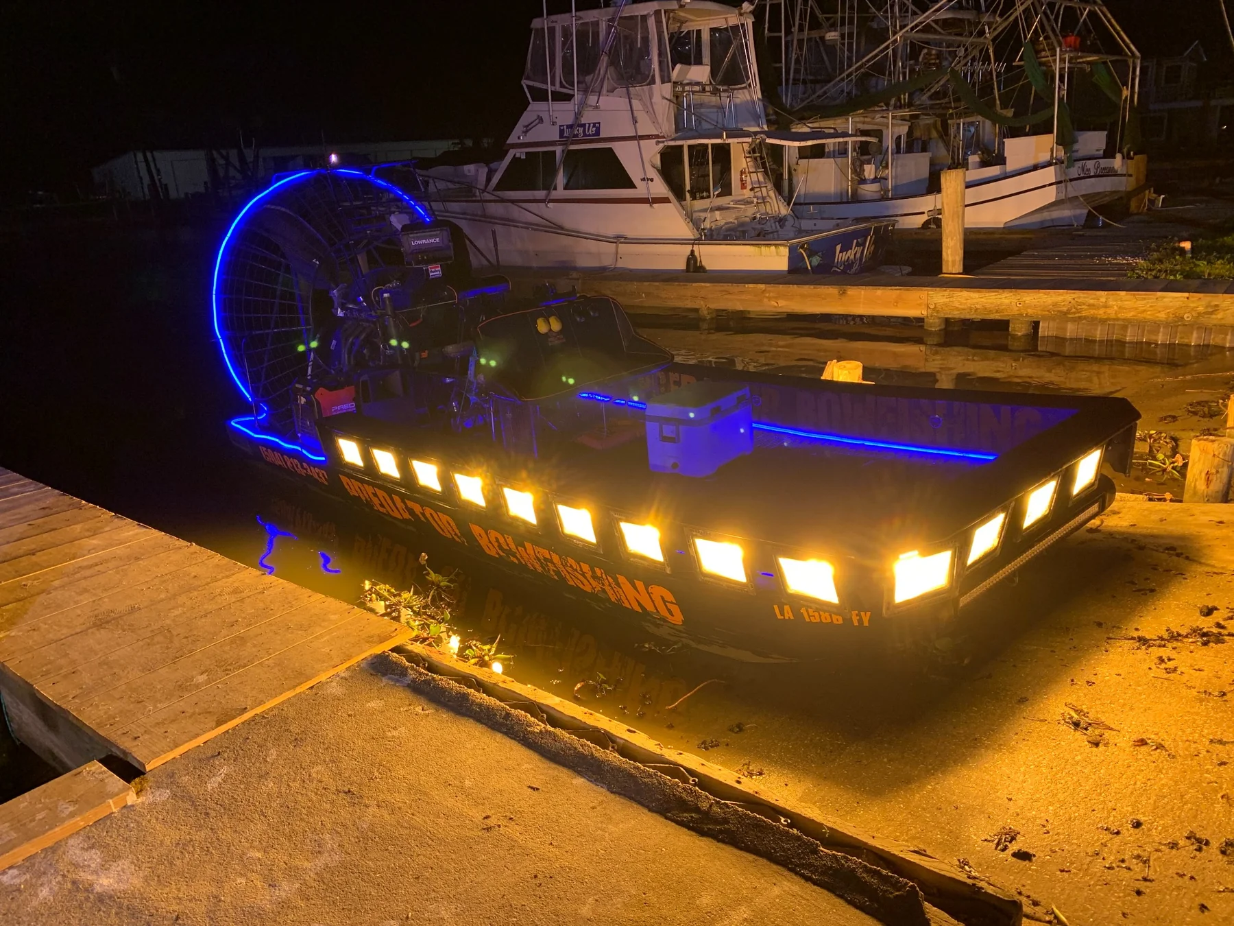 Predator Bowfishing boat illuminated with blue and warm lights at the dock.