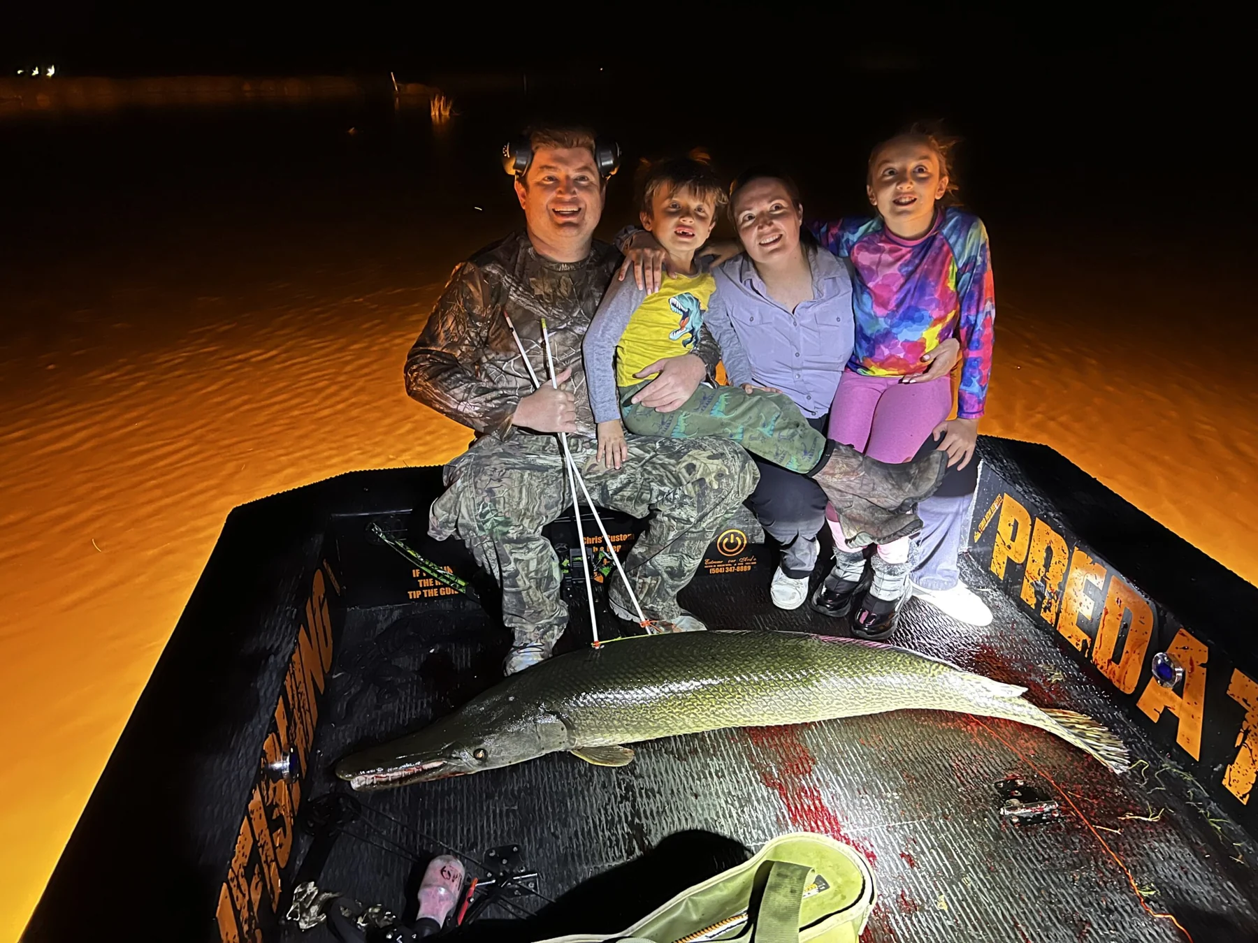 A family aboard a Predator Bowfishing boat at night with their catch.