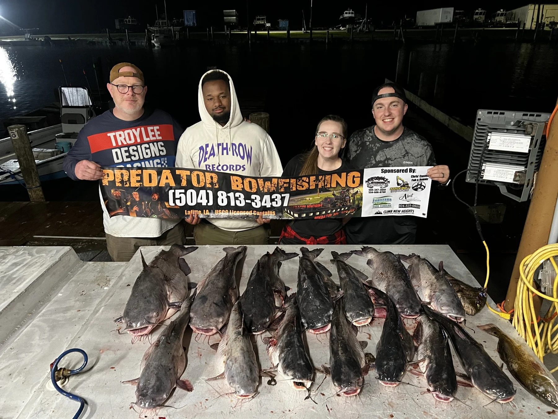 The group from the first trip behind a catch table and Predator Bowfishing sign.