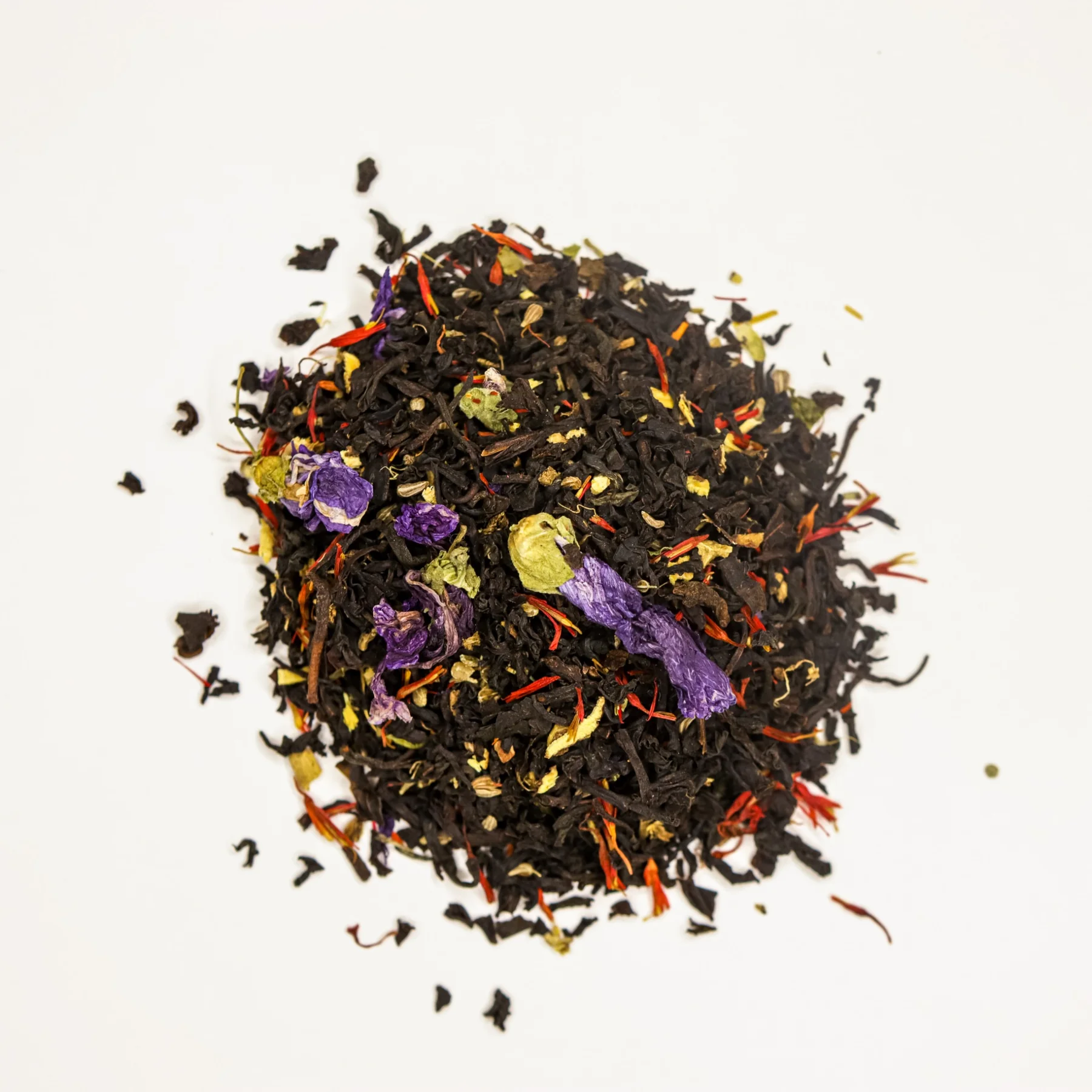 Loose-leaf tea mixed with colorful flower petals on a light background.
