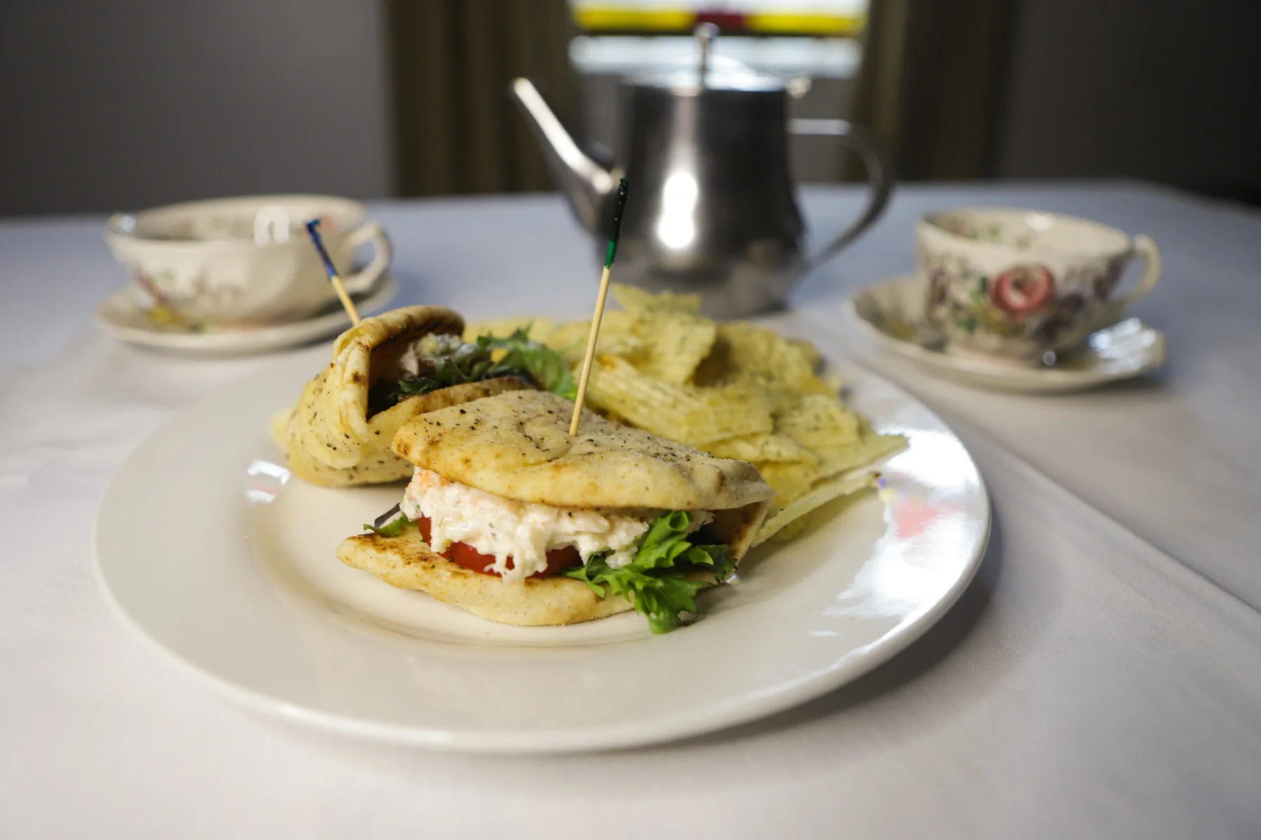 A plated sandwich with teapot and patterned china.